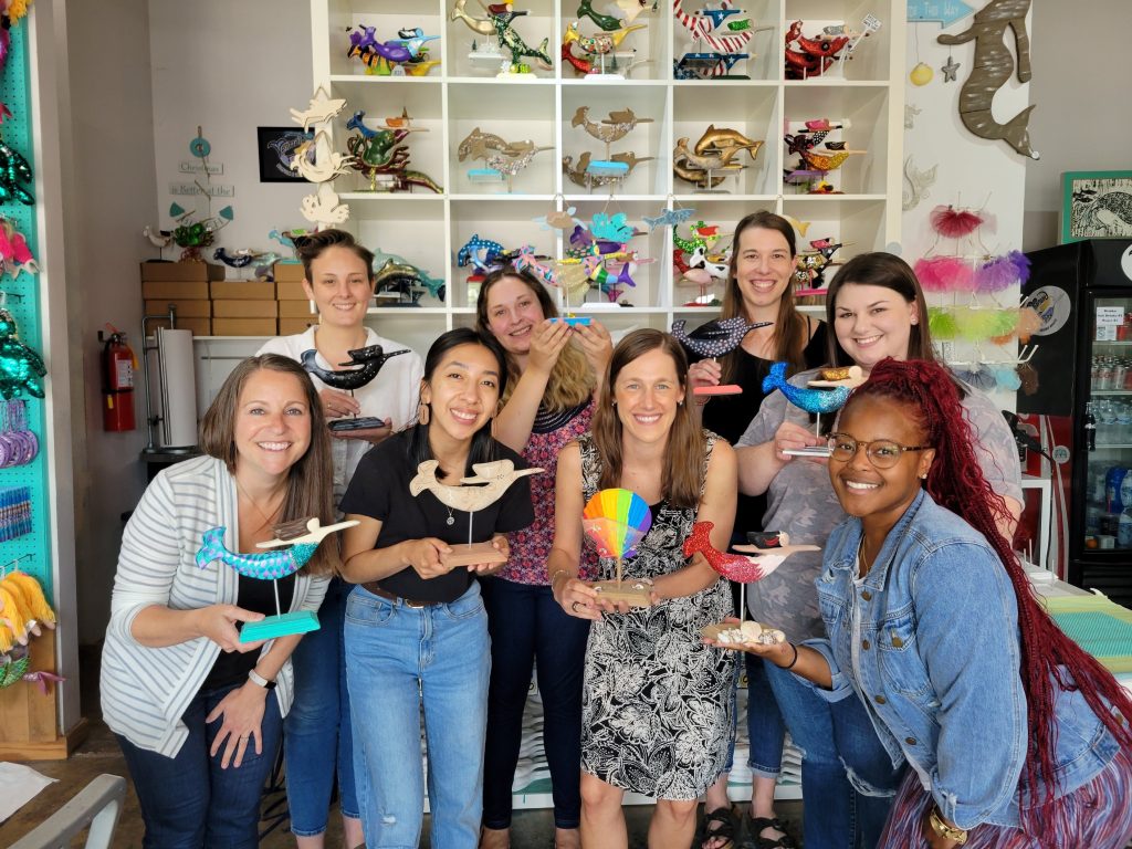 Lab members of ETOH and HaBiT holding their mermaid or seashell statues they painted. 