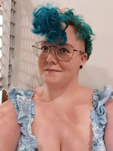 picture of "Ashlyn Currie", a woman with flue hair and glasses.