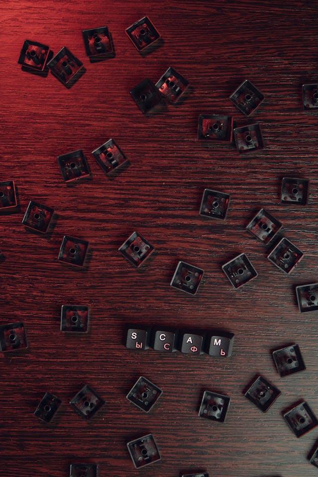 Loose keyboard keys spelling scam. Photo by Mikhail Nilov: https://www.pexels.com/photo/wood-light-red-people-6964173/